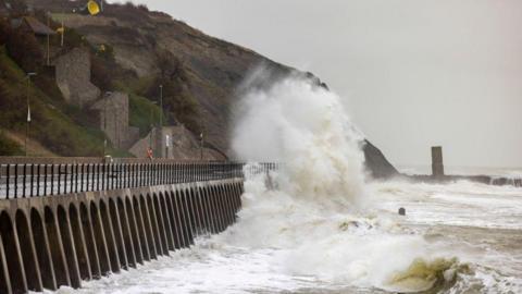 A waves crashing over a sea defence promenade during a storm