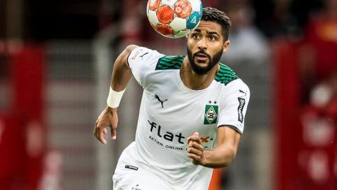 Keanan Bennetts in his white Borussia Monchengladbach kit runs after a bouncing ball during a match