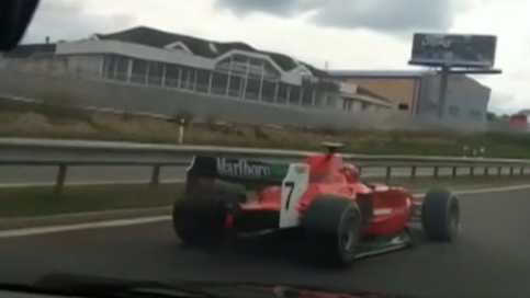 A red racing car decked out in red Ferrari livery and emblazoned with the number 7 speeds down a motorway