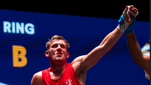 Will Hewitt, in his red England boxing vest, has his arm lifted in victory by the referee.