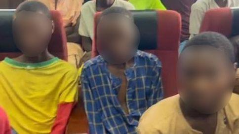 Three young men sit a Nigerian court, two wear yellow tops and one wears a blue shirt. Their faces have been blurred to protect their identities.