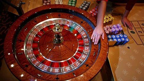 A roulette wheel, showing the red and black numbers. There are chips in different colours to the right. A hand is visible spinning the wheel.
