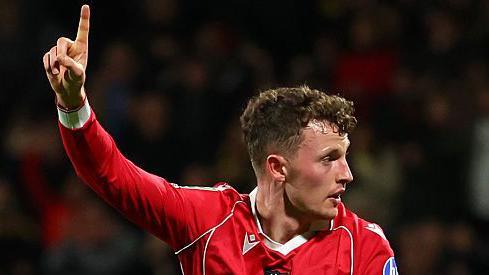 Nathan Broadhead raises his right arm in celebration after scoring