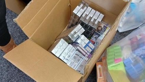 A cardboard box full of silver packaged cigarettes.