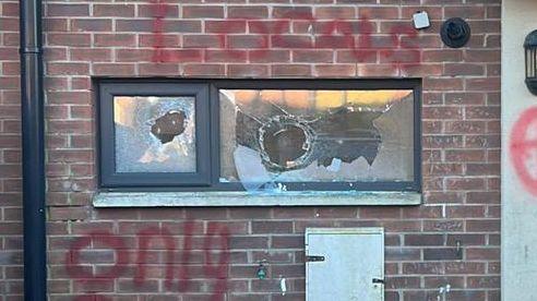 A broken window on a house with the words Locals Only sprayed above and below it in red spray paint