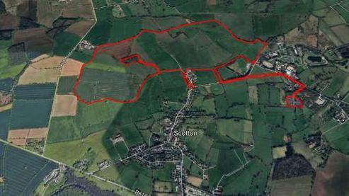An aerial view of fields and villages with a red outline showing the border of the proposed site.
