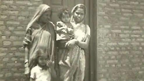 A black and white photo of two women and children. Sarita Paik wearing a sari seen holding toddler Shailaja Paik in her arms