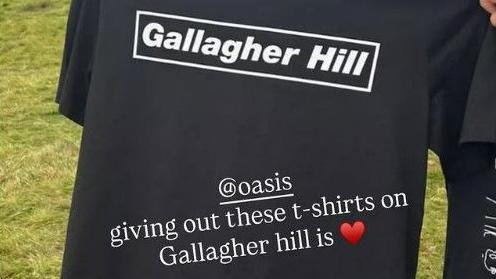 A picture of a black T-shirt with the words 'Gallagher Hill' in white lettering, with an Instagram caption reading '@Oasis giving out these t-shirts on Gallagher Hill is' followed by a heart emoji.