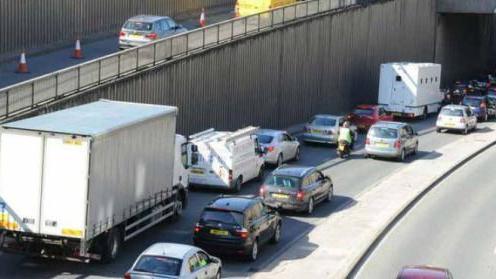 A slightly grainy photo of two rows of queueing traffic, including a large white lorry.