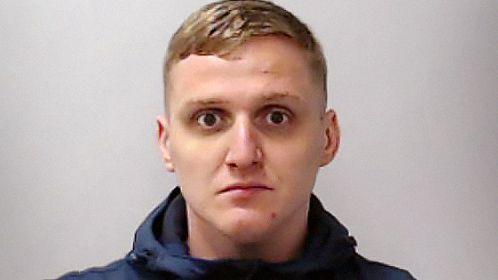 Mug shot of Gavin Coull, who has blonde hair, a blue hoodie and dark circles under his eyes