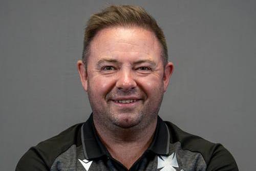 Man smiling at the camera and wearing a black polo 