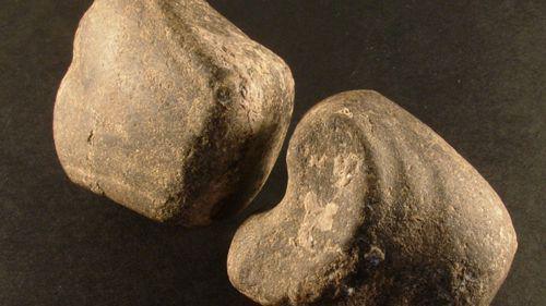 Two pieces of a smoothed stone that was one a battle axe.