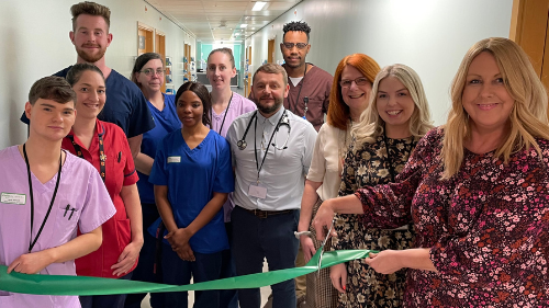 Teresa Cope cutting a ribbon in front of Manx Care staff