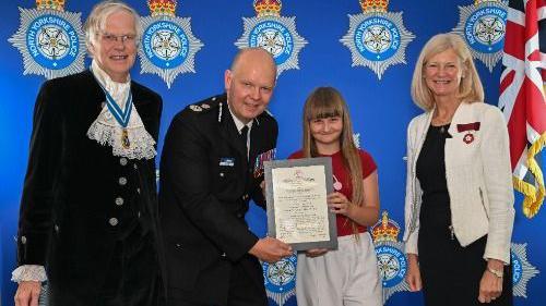 Lulu is presented with the Royal Humane Society certificate by Chief Constable Tim Forber alongside the High Sheriff for North Yorkshire, Sir Andrew Lawson-Tancred and Deputy Lieutenant for North Yorkshire, Clare Granger.
