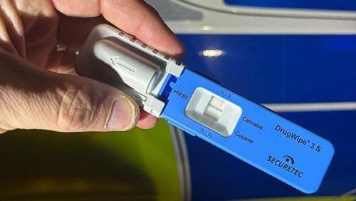 A breathalyser test held against a police car