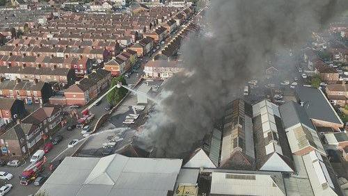 An aerial view of the black smoke billowing out into the sky from above an industrial unit in 