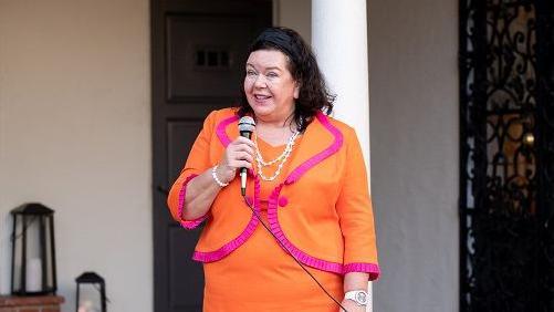 British Ambassador to the US Dame Karen Pierce, clutching a microphone and wearing a bright orange dress and jacket with red trimming attends the BAFTA mentorship program launch with the British ambassador and Consul General on December 05, 2021 in Los Angeles, California