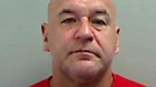 Nigel Harker's mugshot. He is bald and wears a red top.