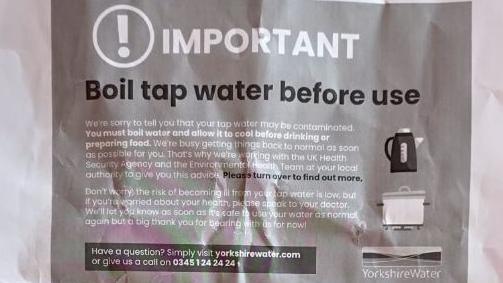 A crumpled black and white paper leaflet with instructions about boiling tap water