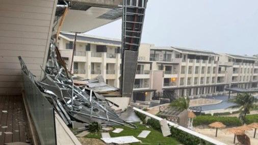 A view from a hotel balcony with some fallen metalwork on the balcony and rows of hotel rooms in the background
