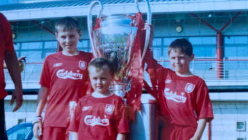 Accrington Stanley forward Josh Woods (front) aged five in his Liverpool kit with the 2005 Champions League trophy with his brothers Connor (right) and Dale (left)