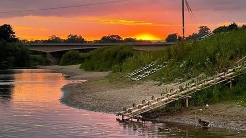 A view of the River Wye as the sun goes down, showing much of the riverbank exposed due to the low water level