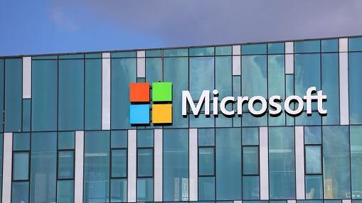 A stock image of the Microsoft office. The words "Microsoft" and the company's logo with orange, green, blue and yellow squares can be seen on a blue building.