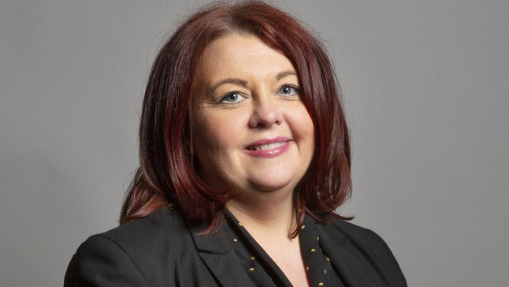 Headshot of Liverpool Wavertree MP Paula Barker. She has shoulder length dark, auburn hair and is wearing a black jacket and a black top with small yellow spots.