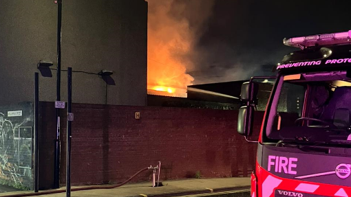 A fire engine with the fire seen burning behind a wall