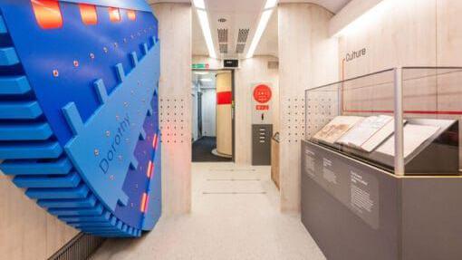 An inside view of the Inspiration train, showing one of the exhibits, a large blue wheel with cogs.