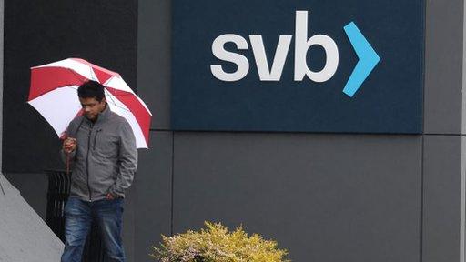 man with umbrella outside bank