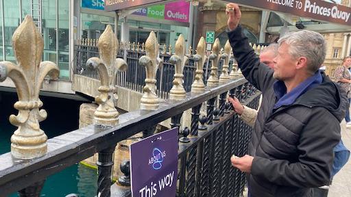 A man throws breads to the fish in front of Princes Quay Shopping Centre.