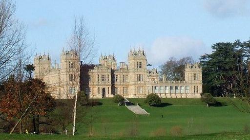 Mentore golf course: A large light brown building sitting behind an area of green grassland. The building has several towers and many windows. Grey steps lead to the entrance.