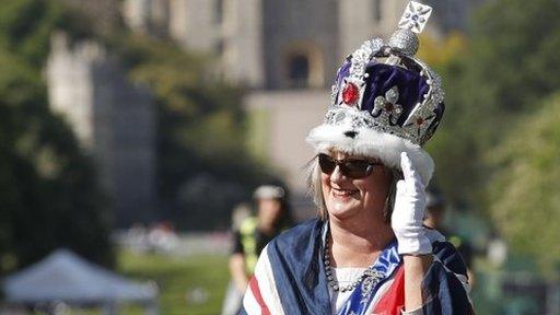 A woman wearing a crown and draped in the Union flag gestures on The Long Walk, in Windsor