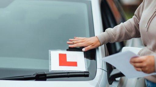 Woman sticking an L plate on her car