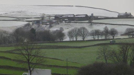 Snow covers high ground in the distance. In the foreground are lower, green fields
