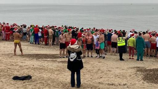 People lining the Felixstowe shoreline before entering the North Sea