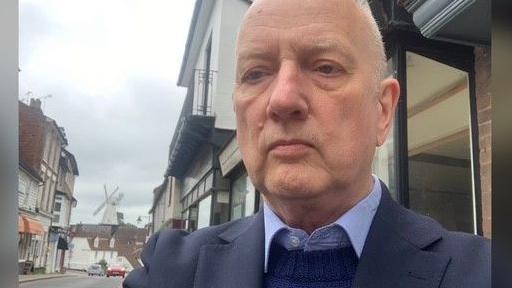 The chairman of the Environment and Transport Cabinet Committee at Kent County Council, Cllr Sean Holden, pictured in a navy suit jacket, a royal blue jumper and a pale blue shirt underneath.