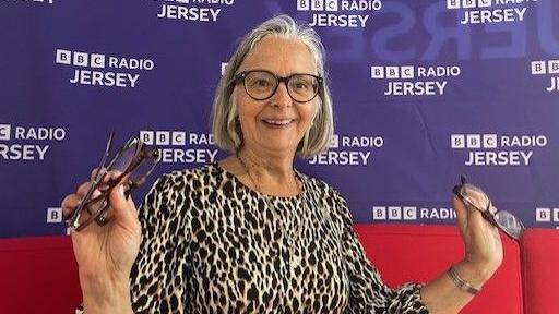 Trena Lewis has a leopard print coloured dress and is sat in front of a BBC Jersey sign. 
