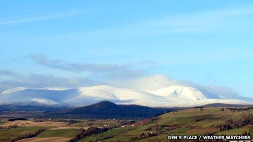 Thick snow covers high hills in the distance. The sky is clear and bright blue