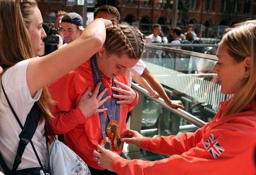 Emma Finucane putting on her three Olympic medals.