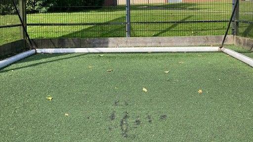 Scuff marks on artificial turf beneath a football goal 