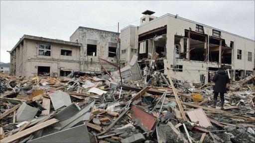 A resident stands on rubble in Ozuchi, Iwate prefecture, on 15 March