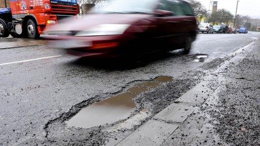 A car driving past a pothole