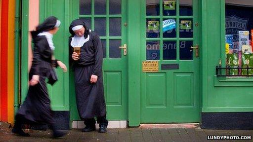 A man dressed as a nun drinks outside a pub