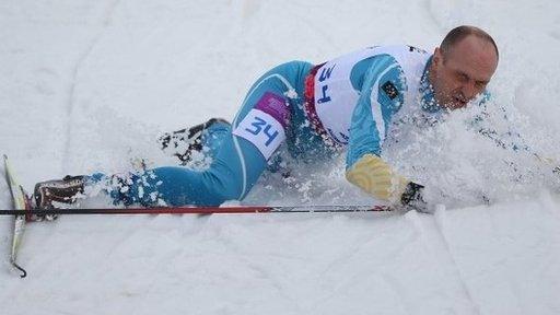 Ukraine's Vitaliy Lukyanenko falls over as he crosses the finish line to win the visually impaired biathlon