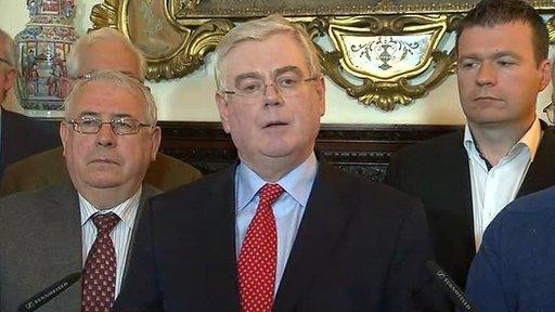 Eamon Gilmore, surrounded by party colleagues, announced he was standing down at a press conference in Dublin on Monday