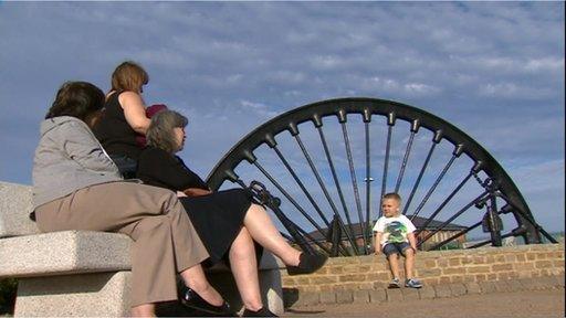 People sitting next to an old pit wheel in Seaham town centre