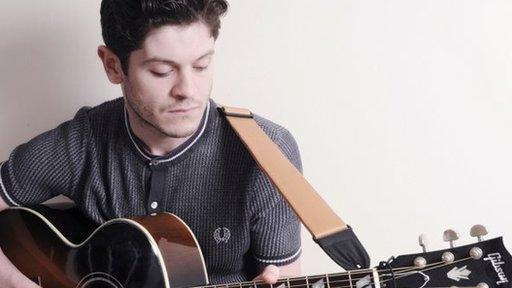 Mae Iwan yn dal i gael amser yn rhywle i afael yn ei gitar!