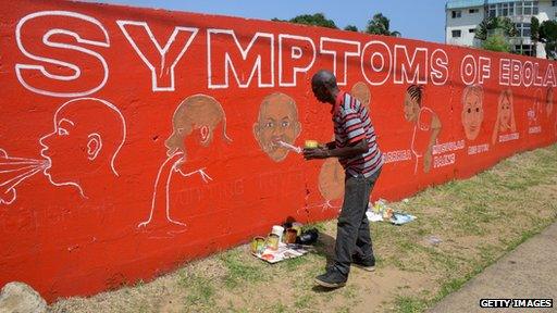 A street artist, Stephen Doe, paints an educational mural to inform people about the symptoms of the deadly Ebola virus in the Liberian capital Monrovia